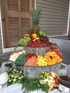 an assortment of fresh fruits are arranged in three tiered trays on a table