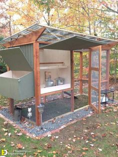 a chicken coop in the middle of a field with trees and leaves on the ground