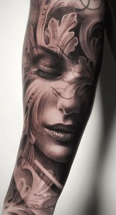 a woman's arm with tattoos on it and an artistic face painted on the side