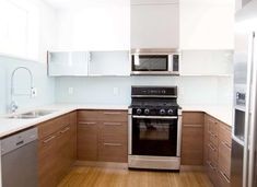 an empty kitchen with stainless steel appliances and wood flooring