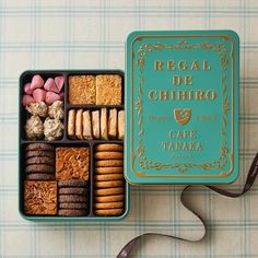 a box filled with assorted cookies and pastries next to a brown ribbon on a table