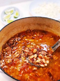 a pot filled with beans and meat on top of a stove