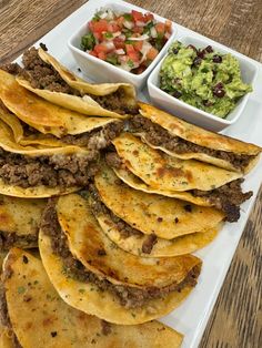 some tacos and guacamole are on a white plate with other food