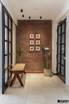 a brick wall with three framed pictures on it and a wooden bench in the middle