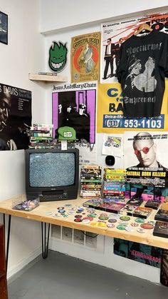 there is a television on the table in front of some posters and t - shirts