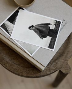 two photographs sitting on top of a wooden table next to a cup and saucer