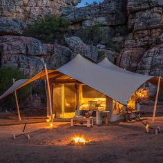 a tent set up in the middle of a rocky area with lit candles around it