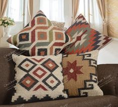 three pillows on a couch with curtains in the background