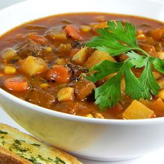 a white bowl filled with soup next to a slice of bread