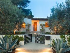 a house with plants and lights in the front yard