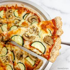 a slice of zucchini and mushroom pizza being lifted from a pan with a spatula