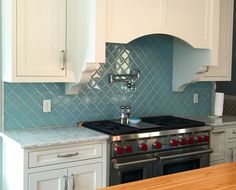 a stove top oven sitting inside of a kitchen next to wooden counter tops and white cabinets