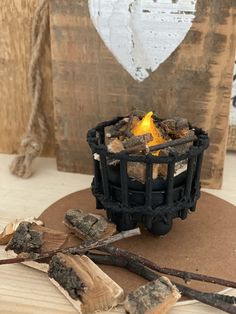 a small fire pit sitting on top of a wooden table next to some sticks and wood