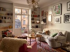 a living room filled with furniture and lots of books on the shelves next to a window