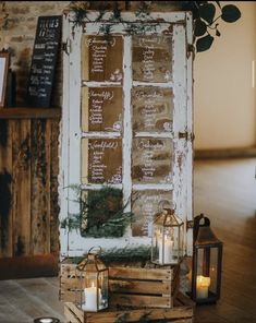 an old door is decorated with greenery and candles for a rustic touch to the table