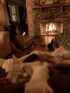 two people sitting on the floor in front of a fire place with a dog sleeping next to them