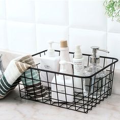 a bathroom sink with soap, hand sanitizers and towels in a wire basket