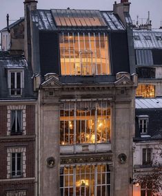 an old building with lots of windows lit up in the evening time, at dusk