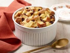 a white bowl filled with bread and raisins on top of a wooden table