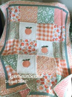 an orange and white patchwork quilt with apples on the front, in shades of peach