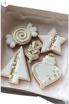 decorated christmas cookies in a box with white and gold trimmings on the top