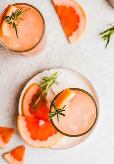 two glasses filled with grapefruit and rosemary garnish