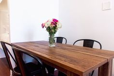 a wooden table with chairs around it and a vase full of flowers on the table