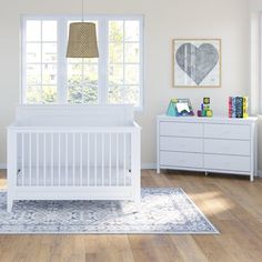 a white crib in the corner of a room with wooden floors and large windows