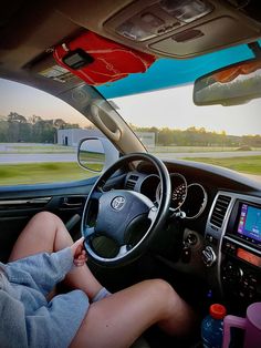 a person sitting in the driver's seat of a car with their feet on the steering wheel