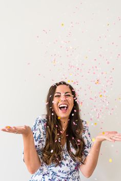 a woman with confetti on her face and hands in front of white background