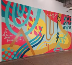 a large colorful painting on the side of a wall in an empty room with metal railings