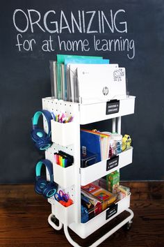 a white cart with books, magazines and other items on it in front of a chalkboard