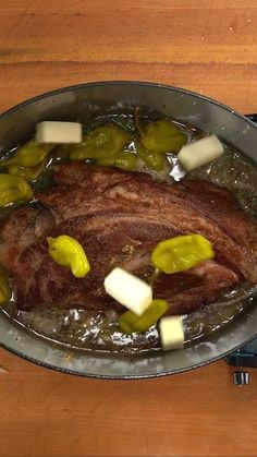 a pot with some meat in it on a wooden table next to an electric device