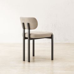 a chair sitting on top of a wooden floor next to a white wall with a black frame