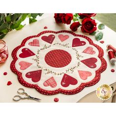 a red and white heart shaped doily on a table with roses in the background