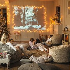 three people sitting on couches in front of a christmas tree with lights around them