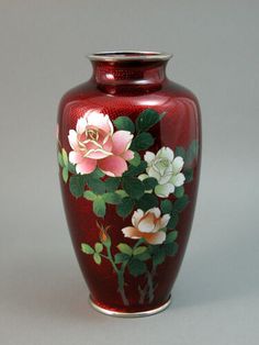 a red vase with flowers painted on it