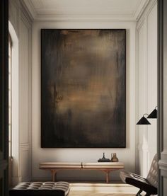 a large painting hanging on the wall above a bench in a room with white walls