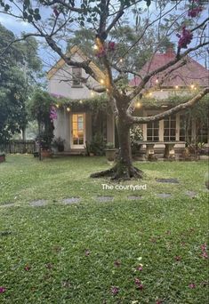 the courtyard is surrounded by lush green grass and trees with lights strung from it's branches