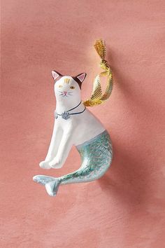 a ceramic cat ornament hanging on a pink wall