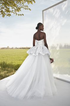 a woman standing in front of a mirror wearing a wedding dress with flowers on it