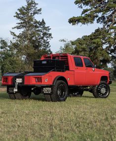 a red truck parked on top of a lush green field