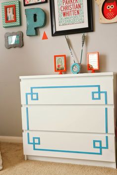 a white dresser with blue tape on it in a child's room decorated with pictures and frames