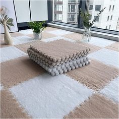 a white and beige rug with some flowers in vases on the floor next to it