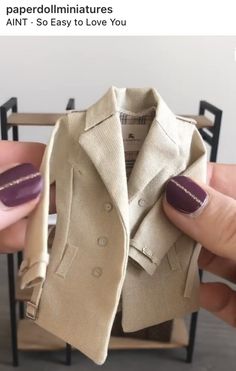 someone is holding up a fake coat in their hand and it looks like they are wearing purple nails