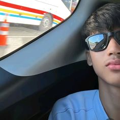 a young man wearing sunglasses sitting in a car