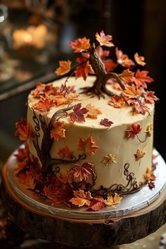 a cake decorated with fall leaves and a tree on top is sitting on a table