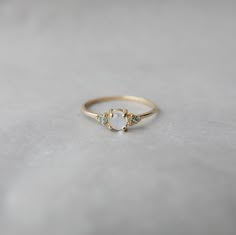 a gold ring with three stones on the front and one stone in the middle, sitting on a white surface