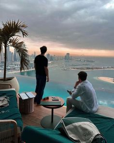 two men sitting on the edge of a swimming pool