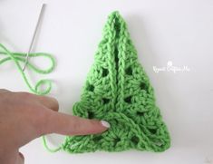 someone is crocheting a christmas tree ornament